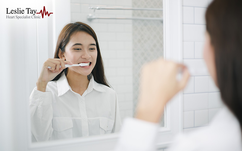 Asian Woman Brushing Teeth And Looking In The Mirror