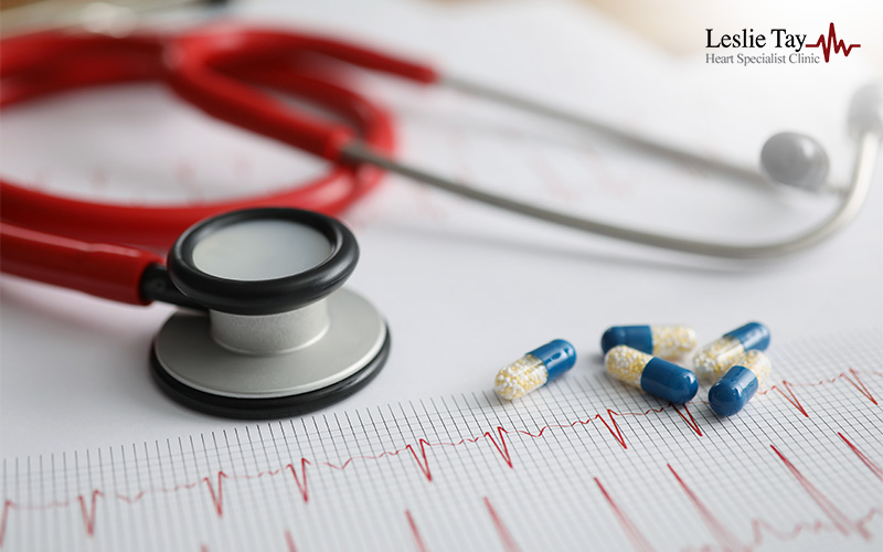 Stethoscope and capsules on an ECG heart rhythm chart.