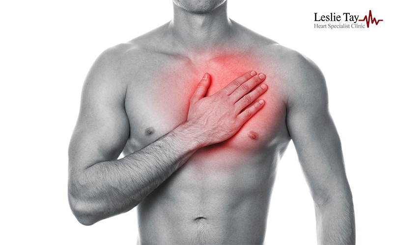 Person clutching chest with red-highlighted heart area, indicating pain or discomfort in a medical context.