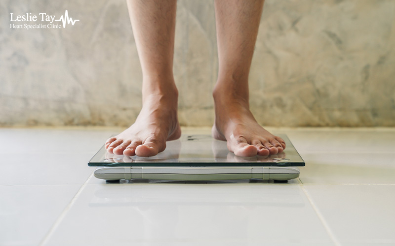 Patient checking weight on scale to manage heart disease risk.